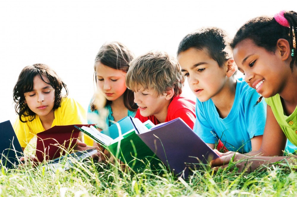Group of kids reading books in the field.
