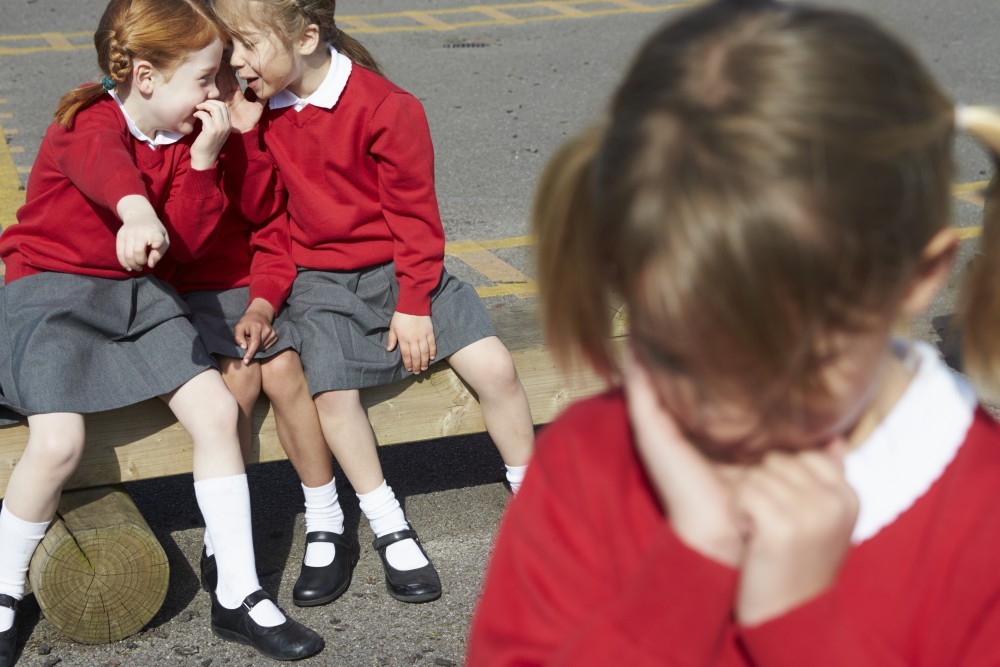 Female Elementary School Pupils Whispering In Playground