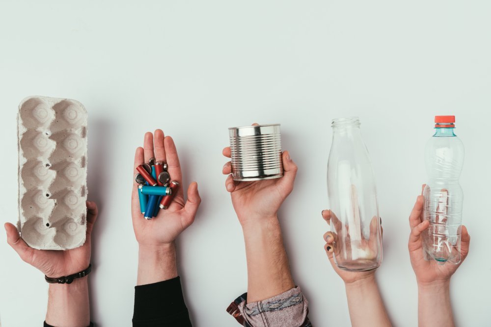 partial view of group of people holding various types of garbage isolated on grey