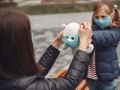 Woman in a disposable mask is teaching her child to wear a respirator