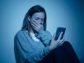 Depressed teenager girl on mobile phone victim of cyberbullying feeling sad, unhappy and lonely