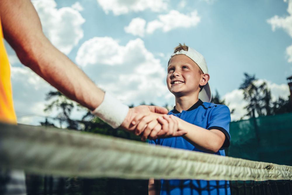 Optimistic child shaking hand of man