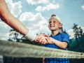 Optimistic child shaking hand of man