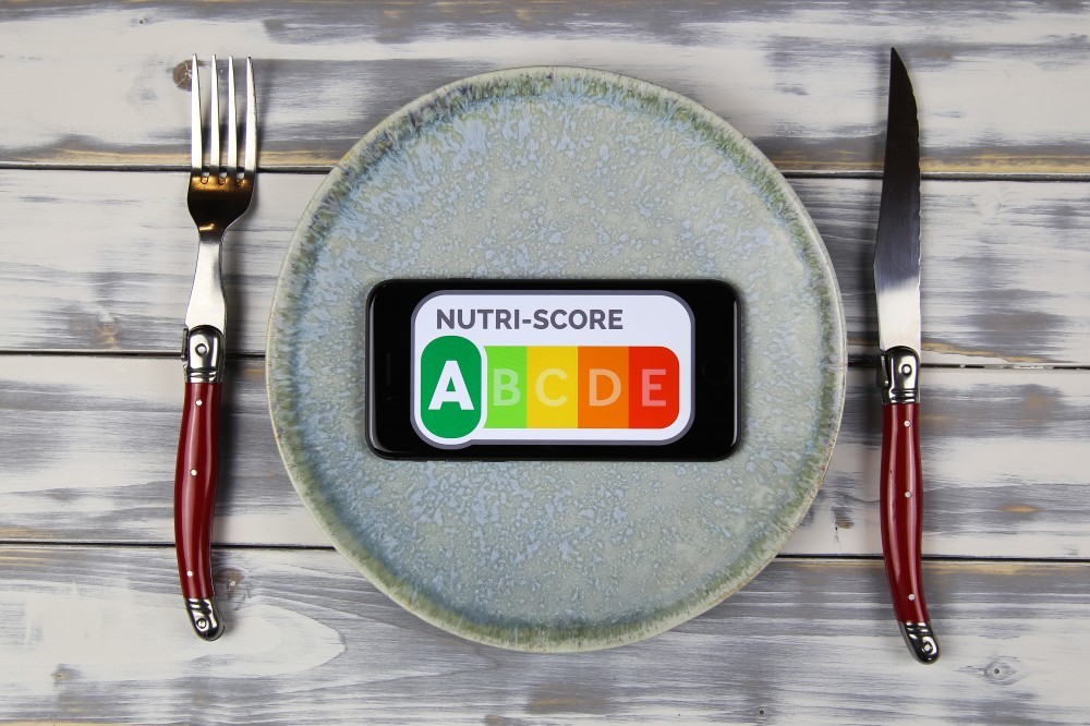 Viersen, Germany - February 9. 2021: Closeup of smartphone screen with logo lettering of nutri-score on plate with cutlery