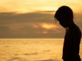 Portrait of sad blond little girl standing on the beach