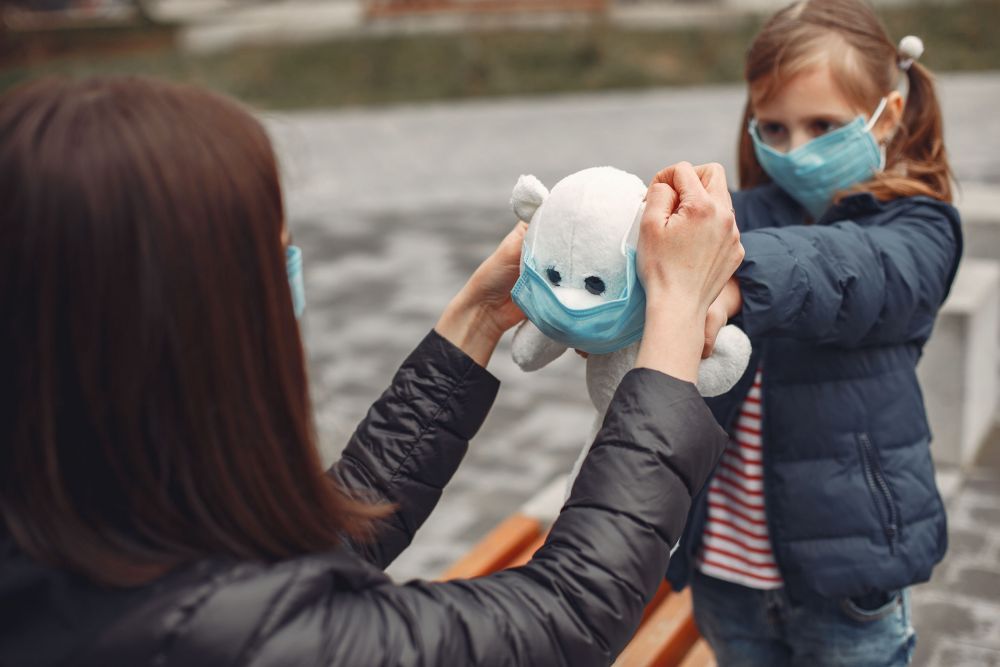 Woman in a disposable mask is teaching her child to wear a respirator