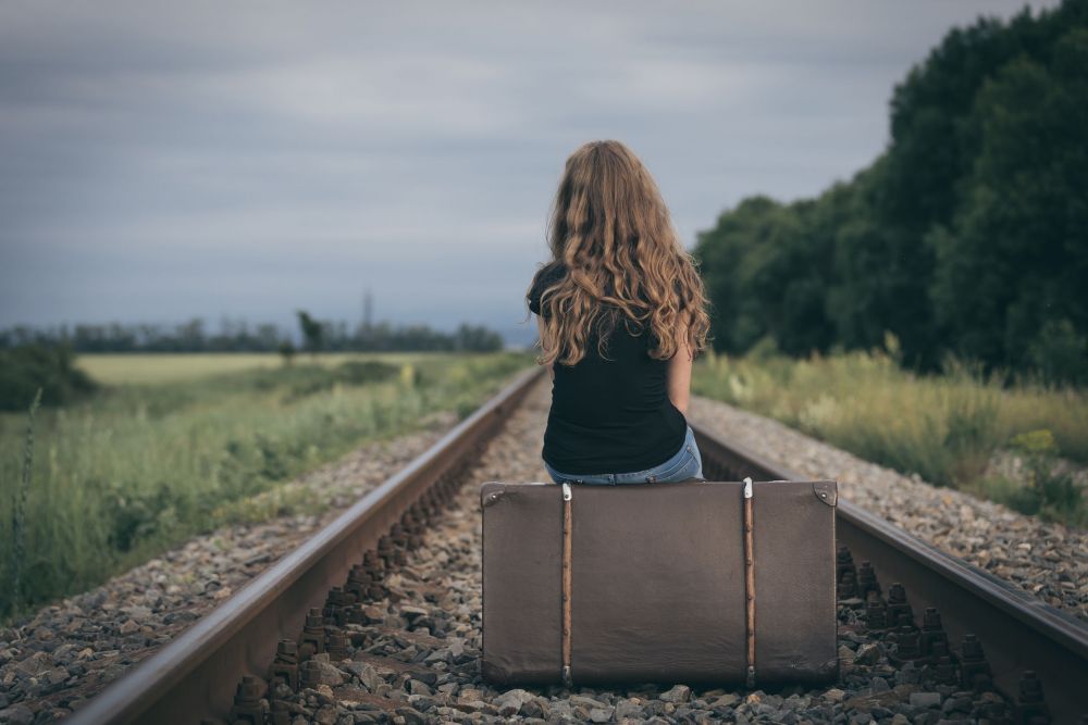 Portrait of young sad ten girl standing with suitcase outdoors at the day time.