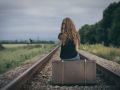 Portrait of young sad ten girl standing with suitcase outdoors at the day time.