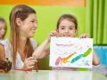 Girl showing self drawn painting in kindergarten