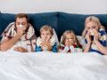 sick young family blowing noses with napkins together while lying in bed