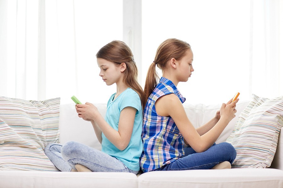 people, children, technology, friends and addiction concept - little girls with smartphones sitting