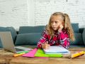 Sweet little schoolgirl having trouble with computer and homework at home