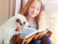 Girl reading book at home with dog