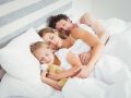 High angle view of parents sleeping with daughter on bed